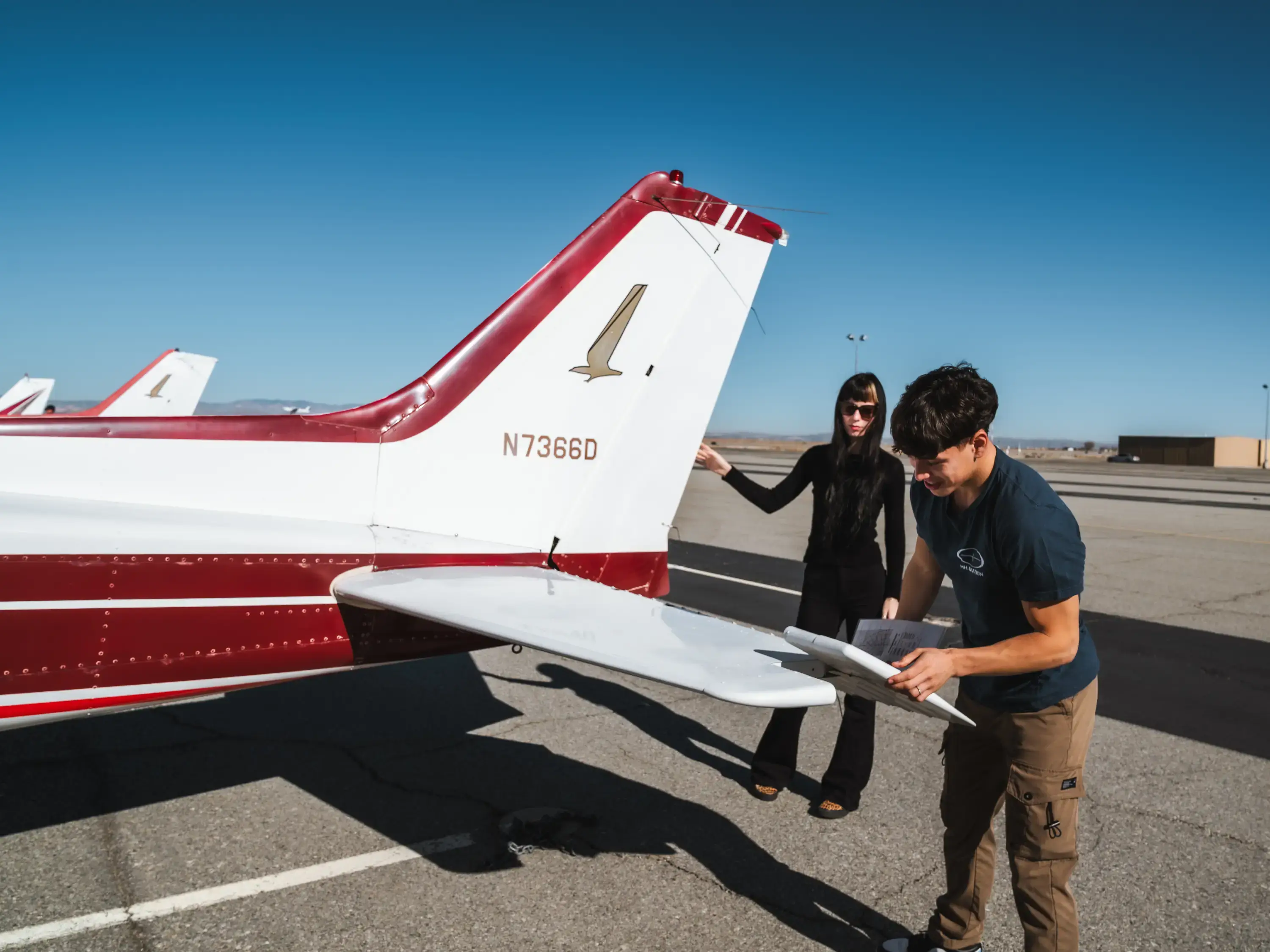 Student and instructor going through a checklist beside the tail of a training aircraft at Fox Field