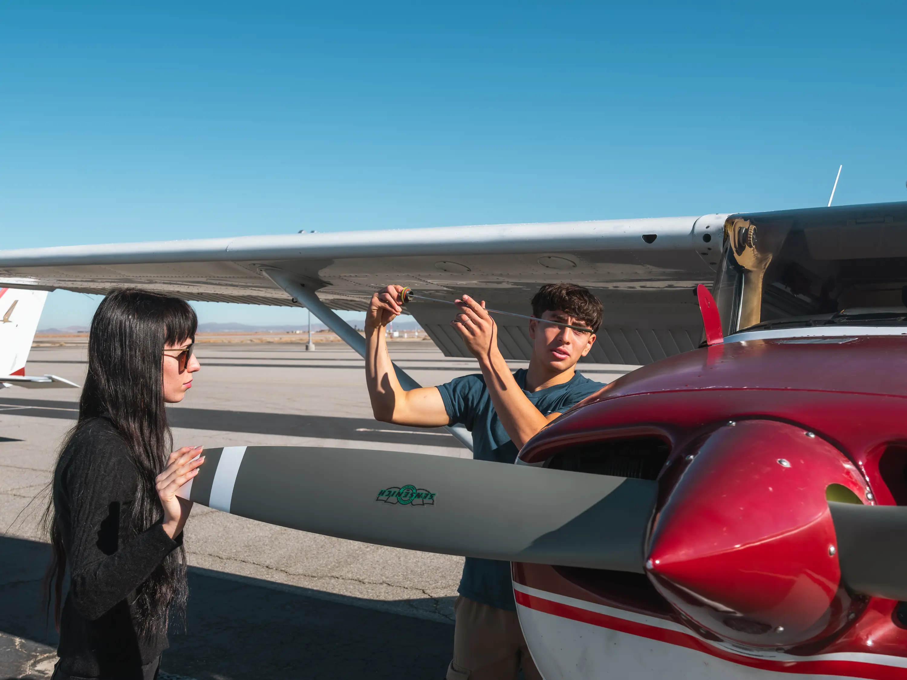 Instructor demonstrating proper preflight inspection techniques on a training aircraft wing