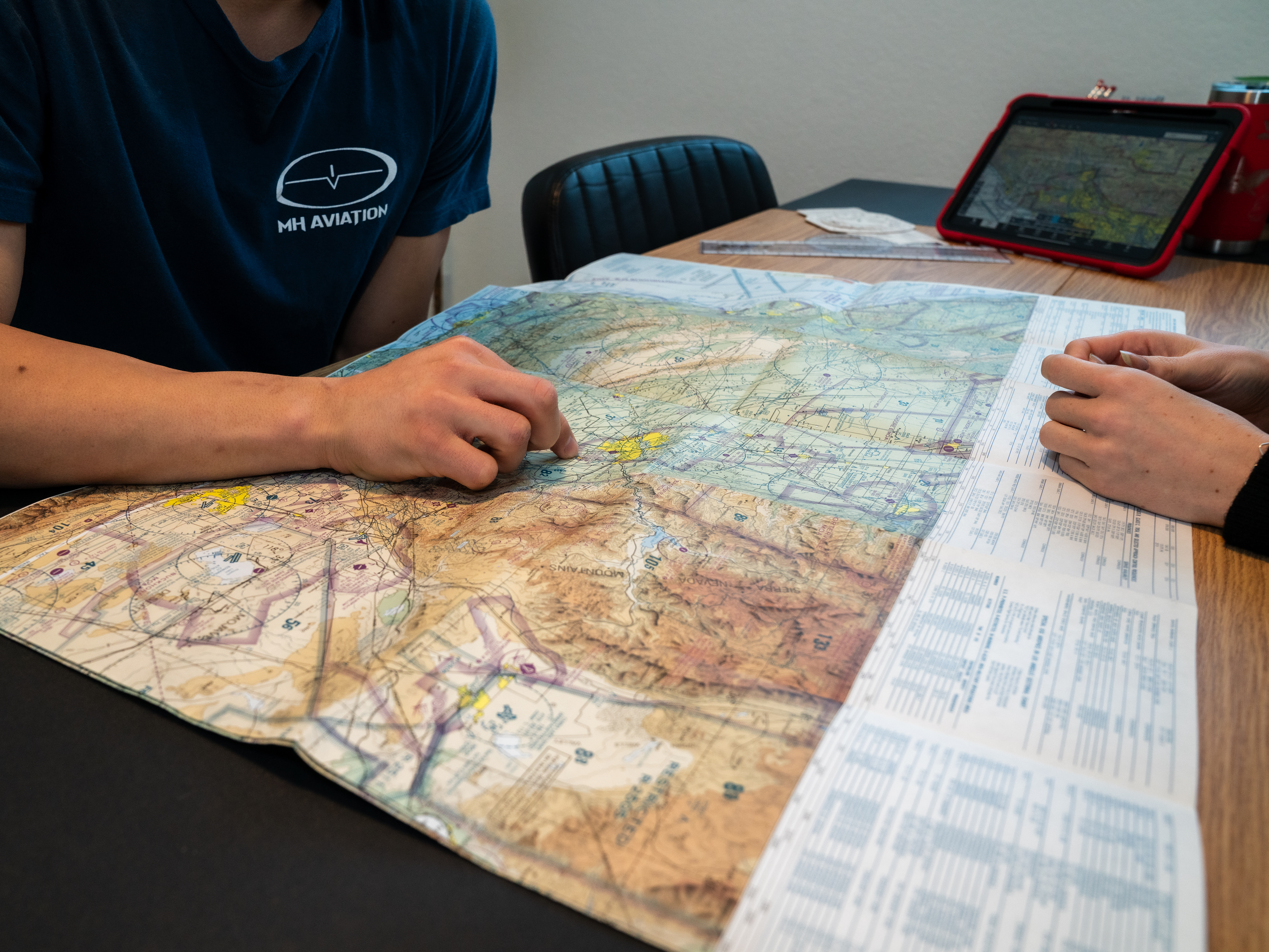 Student and instructor reviewing navigation routes on a paper sectional chart at Fox Field